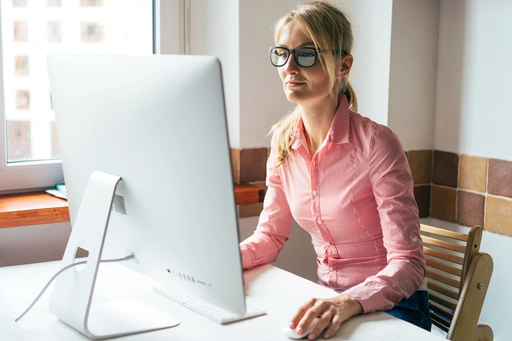 Young pretty woman in glasses analyzing data at her computer