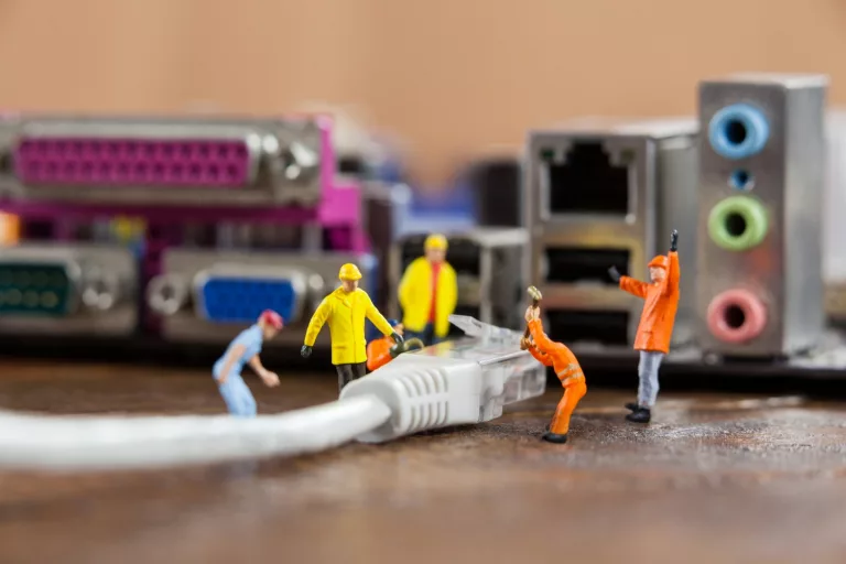 Tiny men working on supersized computer cables and devices.